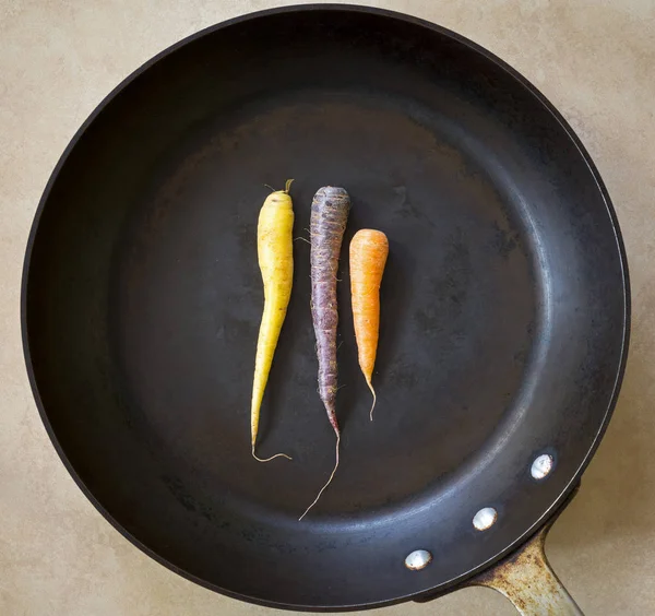 複数の色の大きな黒焙煎鍋にニンジン — ストック写真