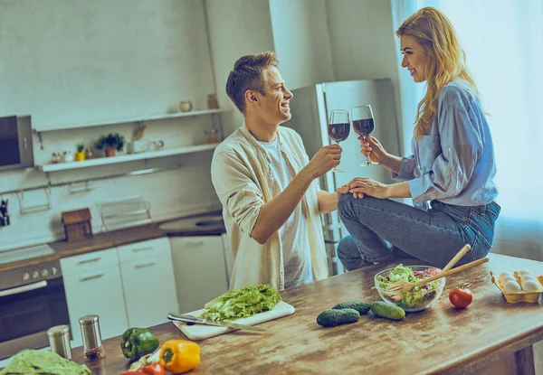 Pareja feliz cocinando comida saludable y bebiendo vino tinto en la cocina de la casa —  Fotos de Stock