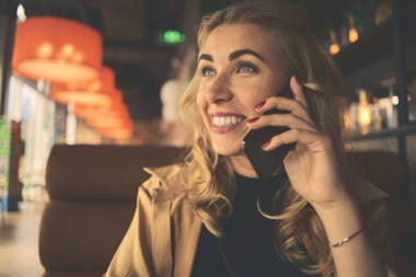 Genç büyüleyici kadın otururken cep telefonu ile arama