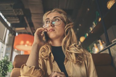 Genç büyüleyici kadın otururken cep telefonu ile arama