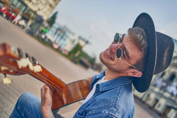 Gitar çalan genç bir adam. Şapkalı şık hippi adam eğleniyor. — Stok fotoğraf