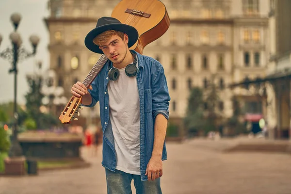 Jongeman loopt op straat met gitaar. Stijlvolle hipster kerel geniet — Stockfoto