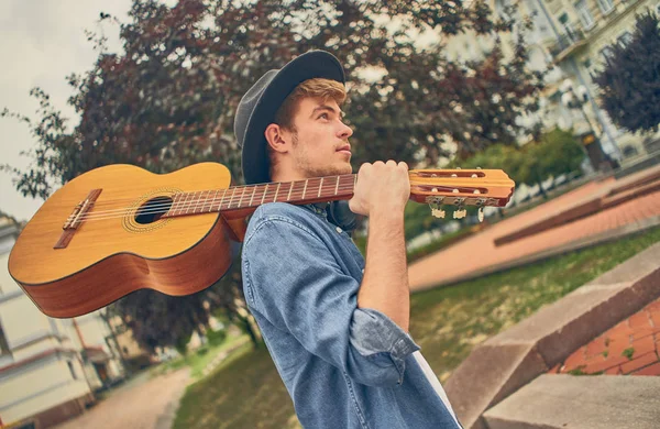 Young man walk at street with guitar. Stylish hipster guy enjoys — Stock Photo, Image