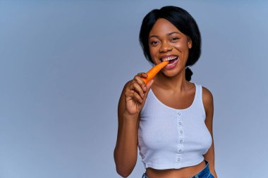 Diyetteki gülümseyen bayan taze havuç ve meyve yiyor.