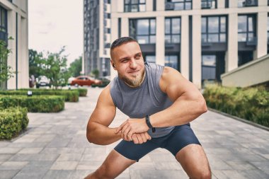 Spor giysileri içinde elinde akıllı bir saatle sabahları sokakta egzersiz yapan dayanıklı bir adam..