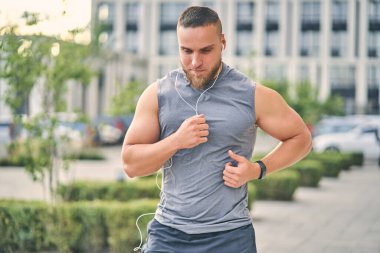 Sporcu gündüz antrenmanı sırasında şehirde koşuyor..