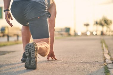 Yarışı başlatmaya hazır bir erkek koşucunun bacağının alt görüntüsü..