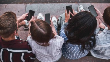 Telefonlarında oyun oynayan dört tanıdığının üst görünümü.