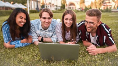 Kampüsteki öğrenciler gün ortasında sokaktaki yeşil halıda dinleniyorlar..