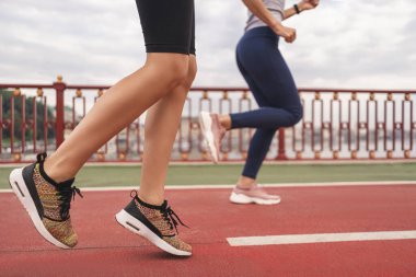 Genç sporcu kadınların sabahları köprüde spor yaparken çekilmiş bir fotoğrafı. Spor konsepti