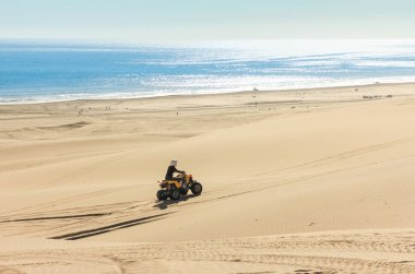Dörtlü araç kullanan insanlar - Okyanus kıyısı, Afrika, Namibya, Namib, Walvis Bay, Swakopmund 'daki kum çöllerinde bir motorcu.