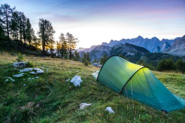 Alacakaranlık saatinde ay ışığı altında bir çadır parlar. Julian Alps, Triglav Ulusal Parkı, Slovenya.