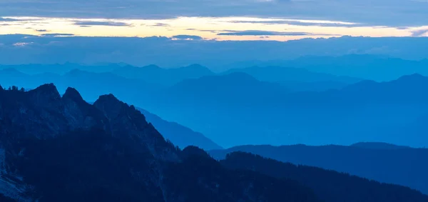 Spektakularny widok na niebieskie pasma górskie sylwetki i mgły w dolinach. Alpy Julijskie, Park Narodowy Triglav, Słowenia. Widok z góry Slemenova, Sleme. — Zdjęcie stockowe