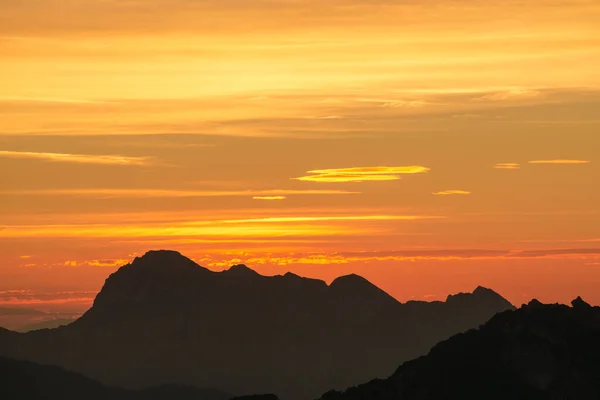 Espectacular silueta montañosa en el crepúsculo naranja al atardecer. Julián Alpes, Eslovenia . — Foto de Stock