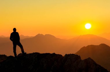 Mutlu başarı kazanan adam gün batımında dağda rahatça ayakta duruyor. Tyrol, Avusturya ve Allgaeu sınır bölgesi, Bavyera, Almanya.