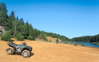 İnsanlar Foyross Gölü 'nün kumlu sahilinde ATV kuadları kullanıyor. Foy, Sudbury, Ontario, Kanada.