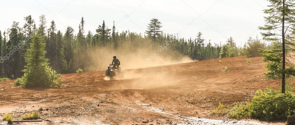 Man driving ATV quad in sandy terrain with high speed.
