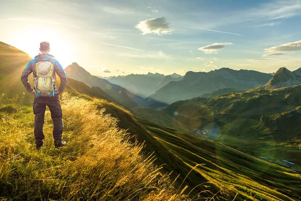 Hombre llegando a la cumbre disfrutando de la libertad. Hermoso amanecer y siluetas de montaña en capas en la mañana temprano. Lechtal y Alpes de Allgau, Baviera y Austria . — Foto de Stock