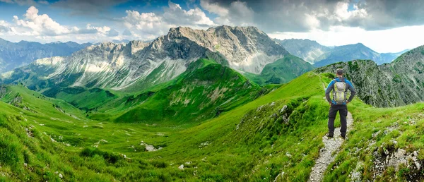 Hombre excursionista en sendero con mochila de pie relajado y disfrutando de vistas panorámicas a las montañas. Alpes, Hohe Gaenge, Allgau, Bad Hindelang, Hinterstein, Baviera, Alemania . — Foto de Stock