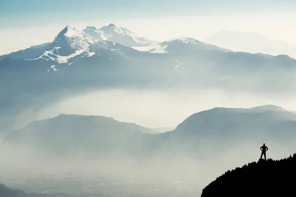 Espectacular siluetas cordilleras. Hombre llegando a la cumbre disfrutando de la libertad. Vista desde la cima del monte Corno di Tres, Tresner Horn hasta Cima Paganella. Trentino, Tirol del Sur, Alpes, Italia . — Foto de Stock