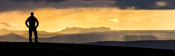 Senderismo Hombre Silueta disfrutando de increíbles montañas coloridas puesta del sol. Fantástico panorama de montañas brumosas y nebulosas con nubes dramáticas. Paisaje montañoso islandés. Islandia . — Foto de Stock