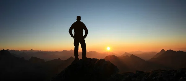 Hombre Silhouette llegar a la cumbre disfrutando de la libertad y mirando hacia las montañas puesta de sol. Allgau Alps, Baviera, Alemania y Tirol Austria . — Foto de Stock