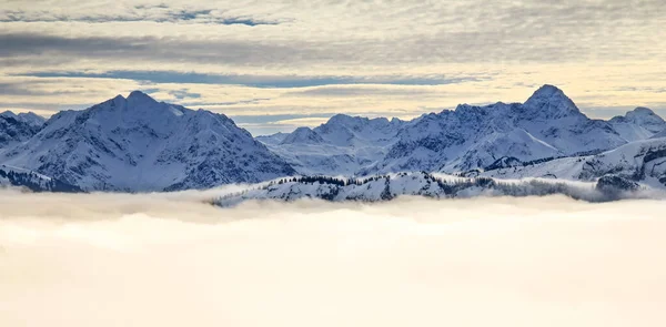 A neve cobriu montanhas com nevoeiro do vale de inversão e árvores envoltas em névoa. Cênica paisagem de inverno nevado em Alpes ao nascer do sol manhã. Allgau, Kleinwalsertal, Baviera, Alemanha . — Fotografia de Stock