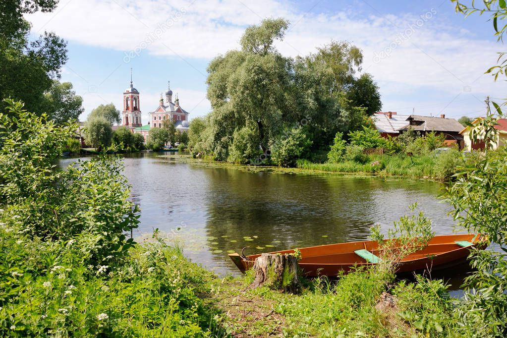 Docked Boat in the Mouth of Trubezh River. The beautiful landscape of Pereslavl-Zalessky with a boat docked on river Trubezh. On the background is rising above trees a church of the Forty Martyrs.