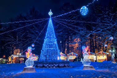 VLADIMIR, RUSSIA - 25 Aralık 2018 - Vladimir şehrinin tarihi merkezi Central Park Lipki 'de saksafon çalan kardan adamlar ve çelenklerle aydınlanan LED ışıkları ile aydınlandı.