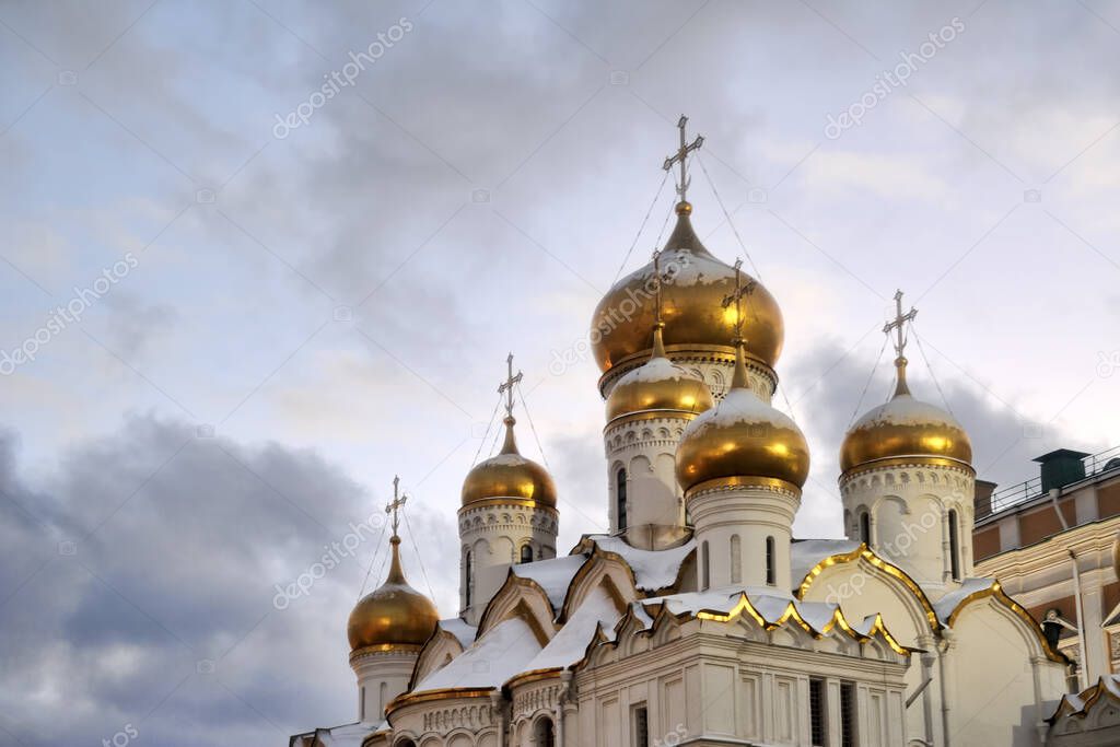 MOSCOW, RUSSIA - Beautiful onion-shaped gilded domes with crosses of Annunciation cathedral of Moscow Kremlin under grey skies in winter twilight.