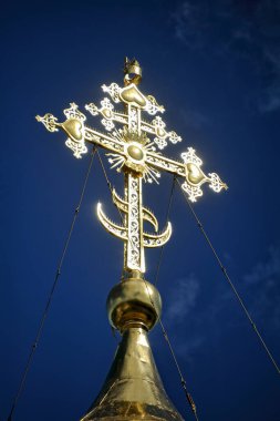 ZVENIGOROD, MOSCOW REGION, RUSSIA - Mavi gökyüzüne karşı Savvino-Storozhevsky manastırında Meryem 'in doğumuna adanmış bir kilise kubbesinin tepesinde güneşin altında parlayan Ortodoks haçı.