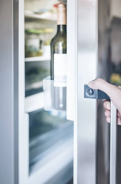 hand opening refrigerator door in kitchen