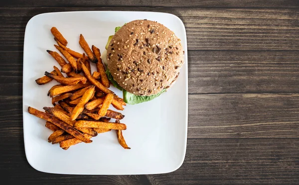 Plate with burger and sweet potato fries on rustic wooden table — Stock Photo, Image
