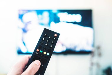 Uzaktan Kumanda Tv karşı beyaz duvara kullanan kişi
