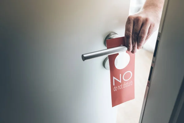 Colocación de la mano roja no molestar signo en el mango de la puerta de la habitación de hotel — Foto de Stock