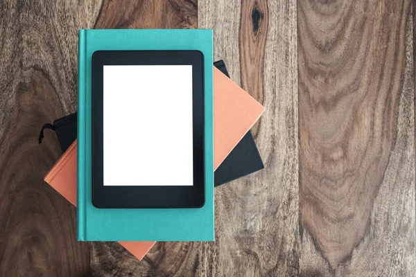 Bovenaanzicht van e-book reader op stapel boeken op houten tafel — Stockfoto