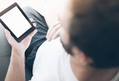 e-kitap okuyucu veya tablet bilgisayar kullanarak koltukta oturan adam omuz görünümü üzerinde