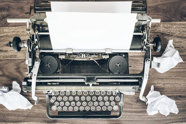 rustik ahşap masa üzerinde eski manuel daktilo ve buruşuk kağıda üstten görünüm
