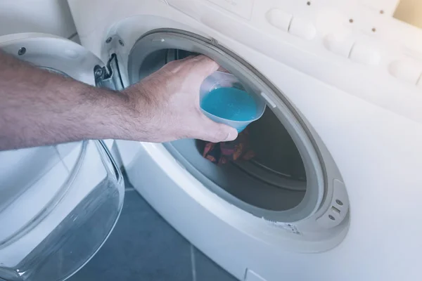 Hand legt Messbecher mit Waschmittel in Waschmaschine — Stockfoto