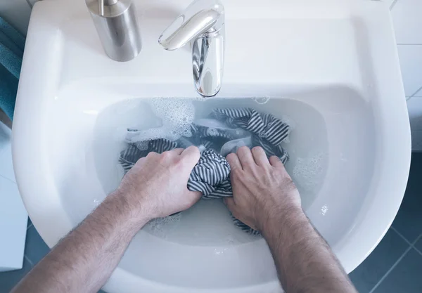 Ansicht von oben: Person wäscht gestreiftes Hemd im Waschbecken von Hand — Stockfoto