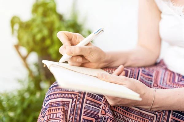 woman sitting on patio taking notes in notebook