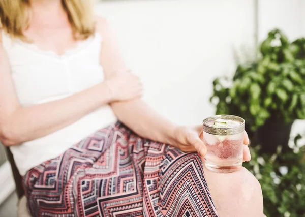 Blonde vrouw ontspannen op de patio bedrijf iced drankje — Stockfoto