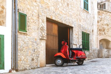 vintage red motor scooter parked in historic spanish village clipart