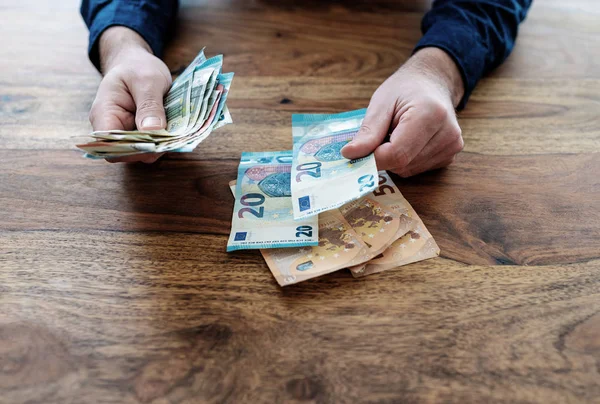 Mann sitzt am Schreibtisch und zählt Geld — Stockfoto