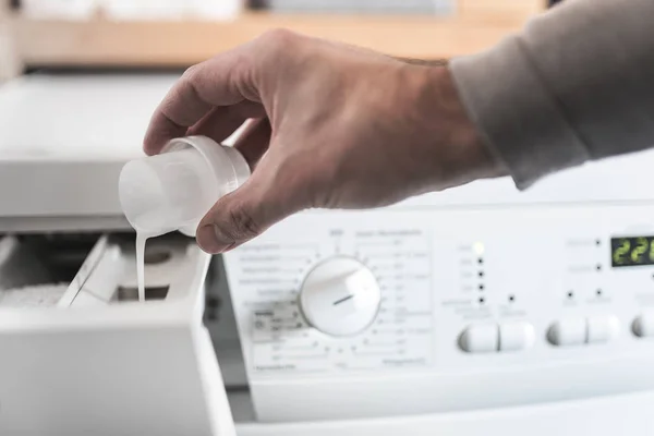 Person mit Dosierhilfe, um Weichspüler in Waschmaschine zu füllen — Stockfoto