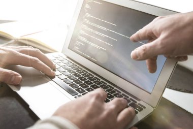 diğer monitöre işaret ediyor iken dizüstü bilgisayar üzerinde çalışan kişi