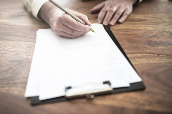 Man undertecknar kontrakt på trä skrivbord — Stockfoto