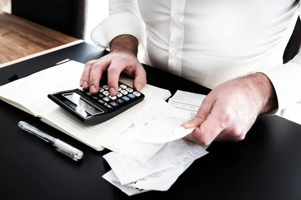 Homem na mesa com calculadora, contas ou talões de vendas e notpad — Fotografia de Stock