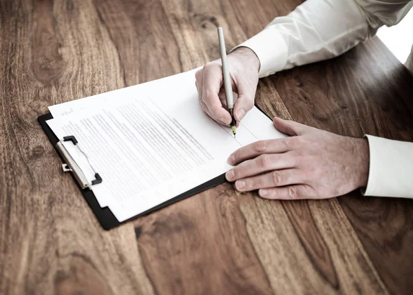 Man signering avtal eller dokument på trä skrivbord — Stockfoto