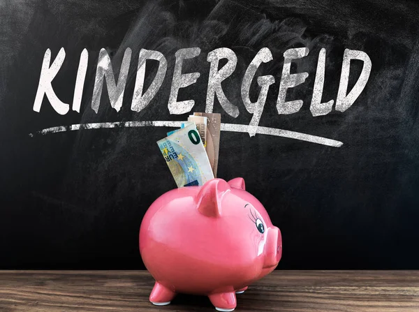 Word Kindergeld, çocuk parası, Almancası blackboard kumbara ve nakit öndeki ahşap masa üzerinde